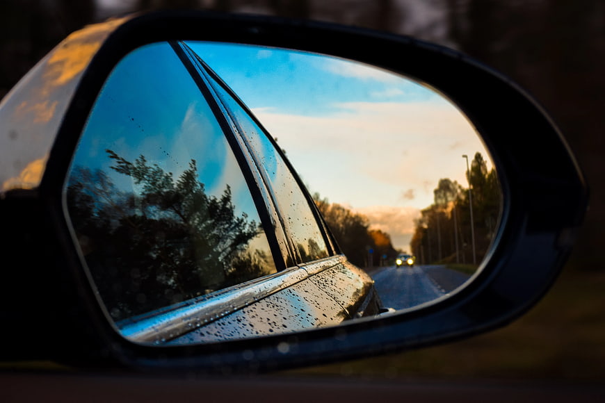 Rainy Road Reflection in Car Side Mirror at Sunset