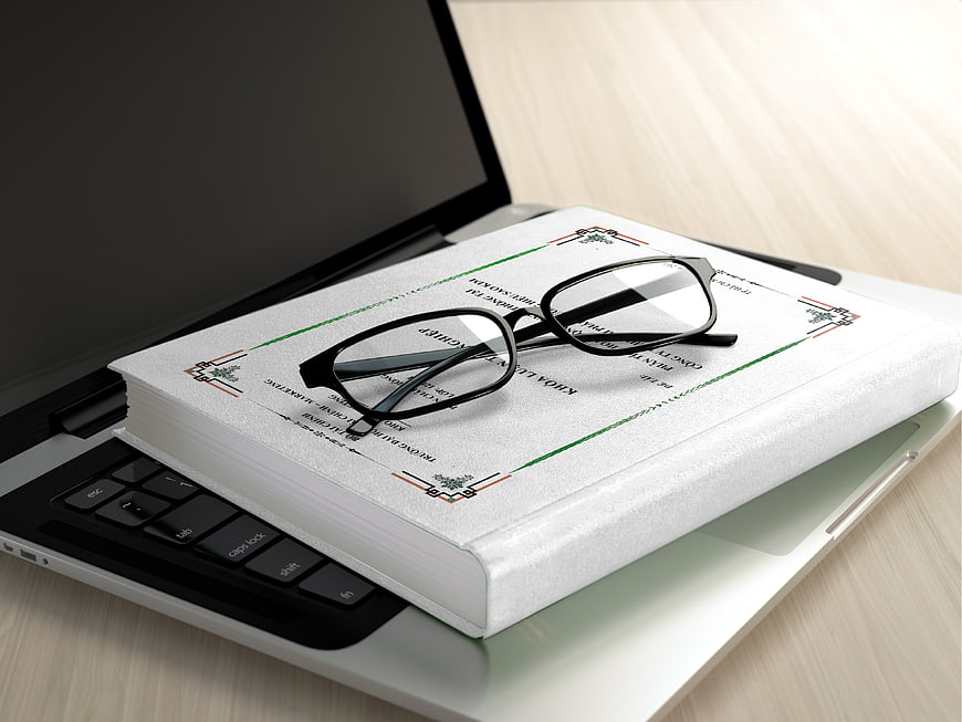 White Book and Glasses on Laptop Workspace