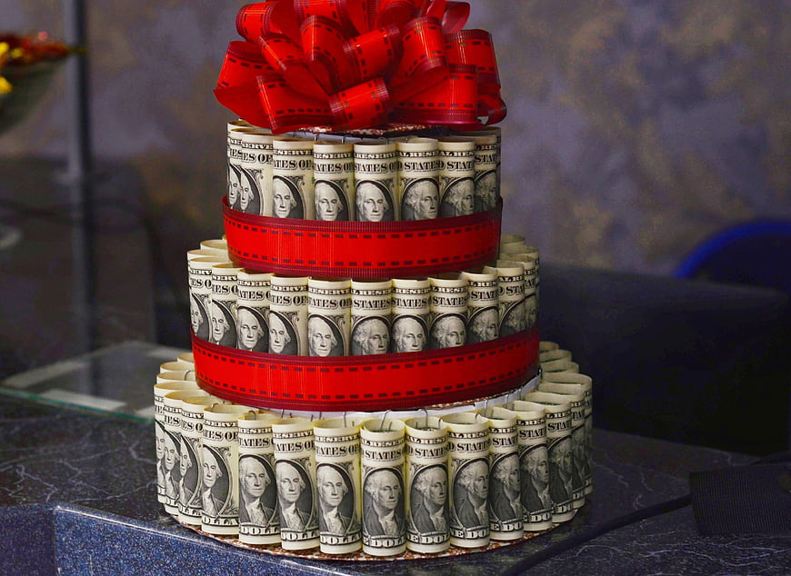 Three-tiered money cake made of rolled hundred dollar bills
