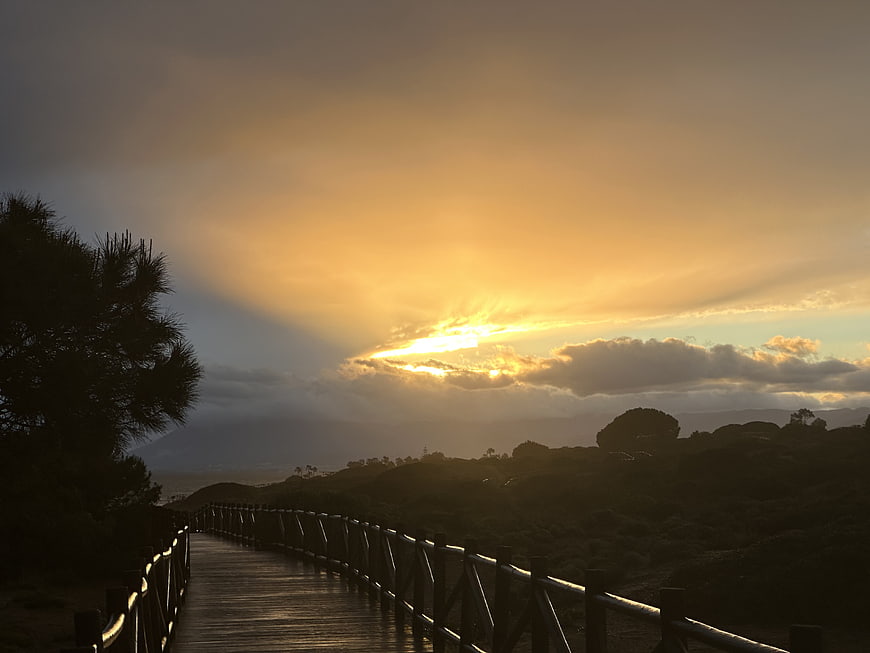 Sunset over wooden boardwalk with dramatic clouds and silhouette