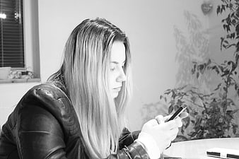 Woman in leather jacket using smartphone indoors