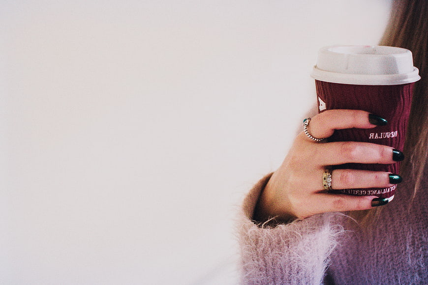 Woman holding coffee cup with green nails