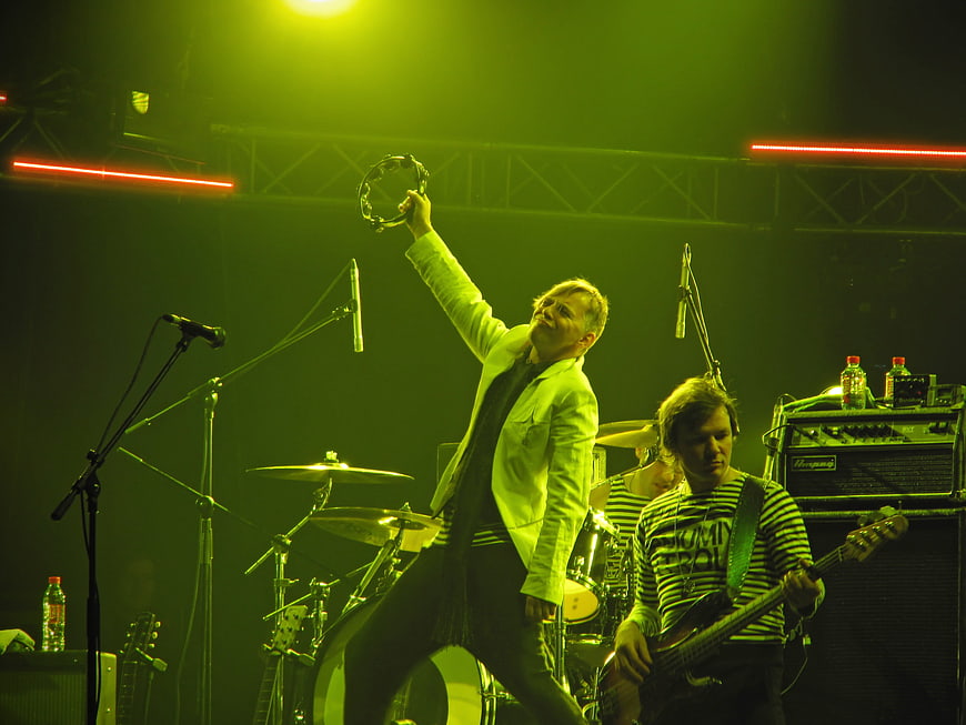 Rock band performing live on stage with green lighting