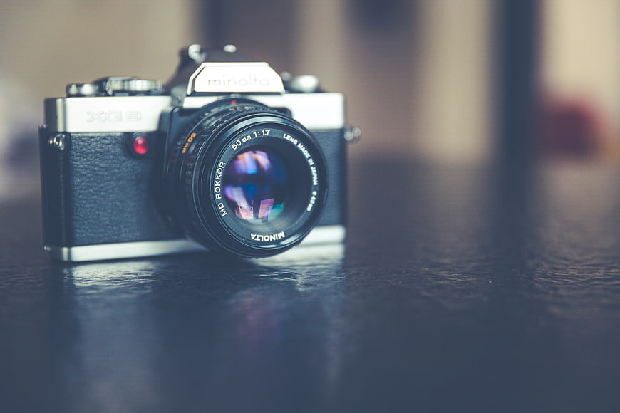 Vintage Minolta XG3 SLR Camera on Dark Wooden Table