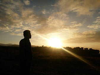 Silhouette of Man Watching Golden Sunset Over Hills