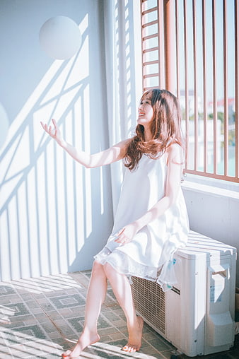 Joyful Woman in White Dress Sitting on Balcony in Sunlight
