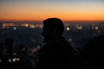 Silhouette of Man Looking at City Lights at Sunset