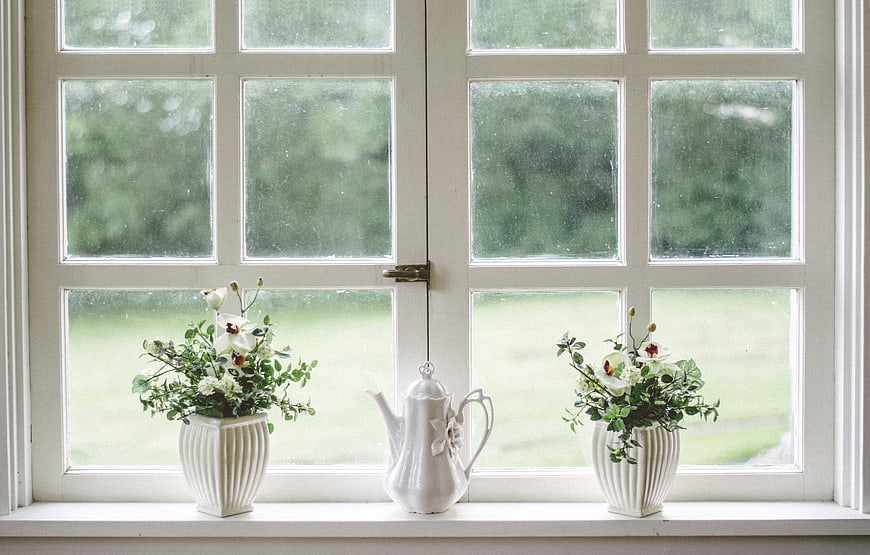 White ceramic teapot and floral arrangements on a window sill