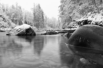Serene black and white winter river landscape with snow-covered rocks