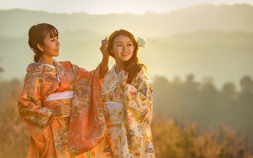 Two Asian Women in Traditional Kimonos Smiling Outdoors