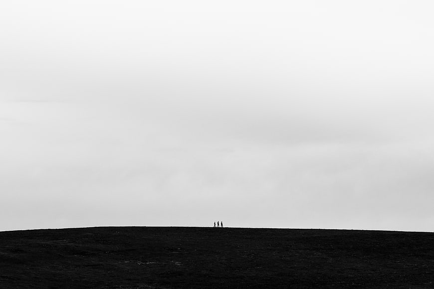 Minimalist black and white landscape with tiny silhouettes on a hill