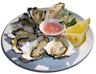 Fresh raw oysters on the half shell with lemon wedges and mignonette sauce