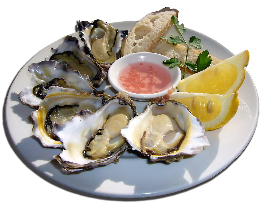 Fresh raw oysters on the half shell with lemon wedges and mignonette sauce