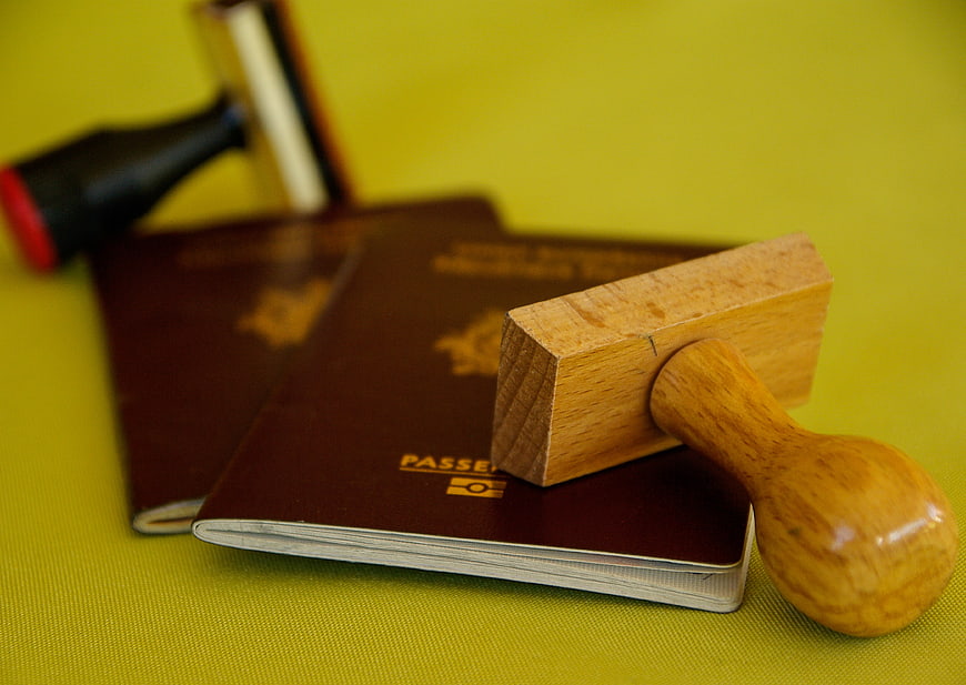 Wooden Stamp on Passports and Gavel on Green Background