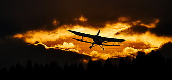 Silhouette of Biplane Flying Against Dramatic Sunset Sky