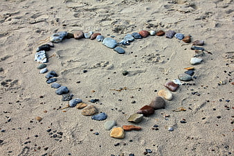 Heart shape made of stones on sandy beach