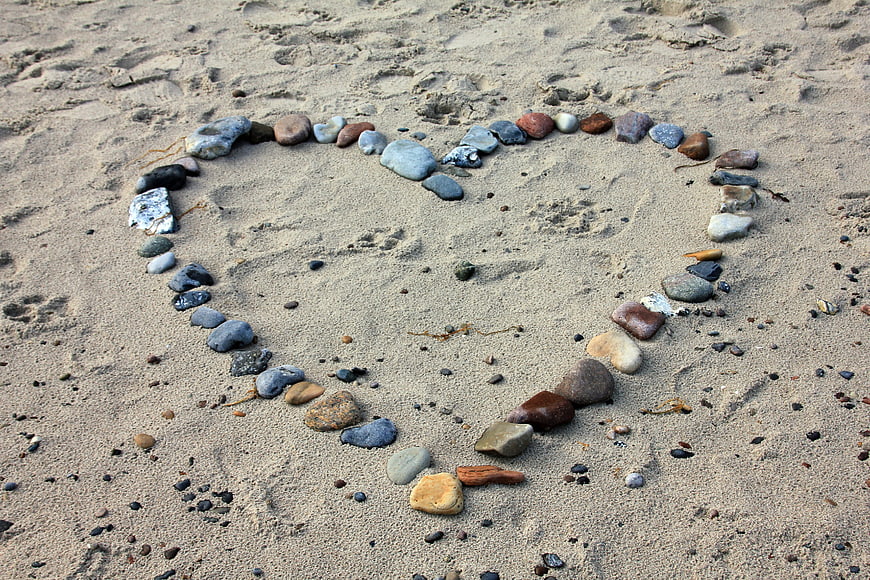 Heart shape made of stones on sandy beach