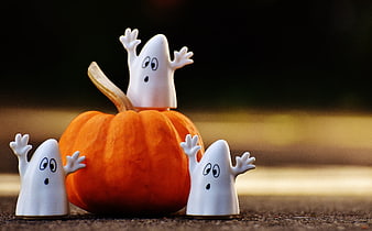 Cute Halloween Ghost Figurines Surrounding Small Orange Pumpkin