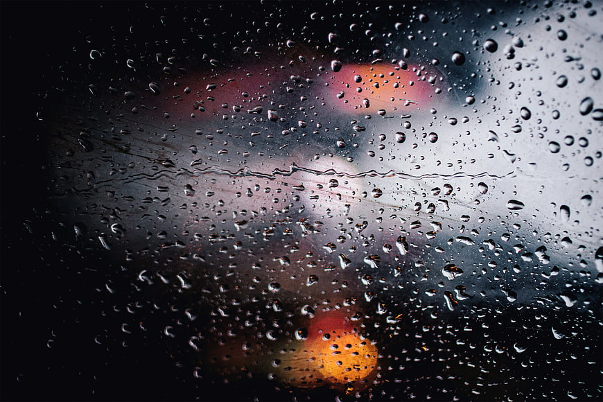 Raindrops on Window Glass with Blurred City Lights