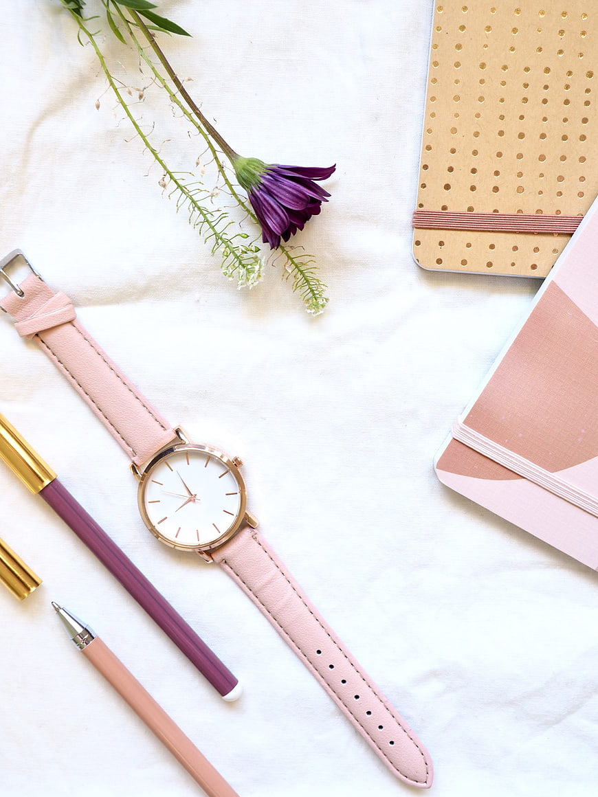 Pink Watch Flat Lay With Notebooks, Pens, And Purple Flower