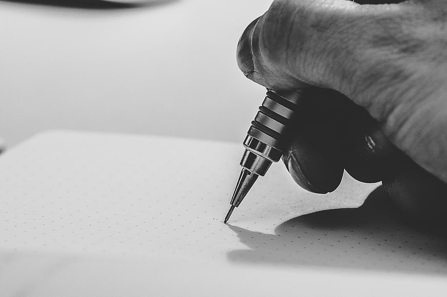 Close-up of hand writing with pen on dotted paper