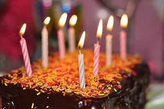 Chocolate birthday cake with colorful sprinkles and lit candles