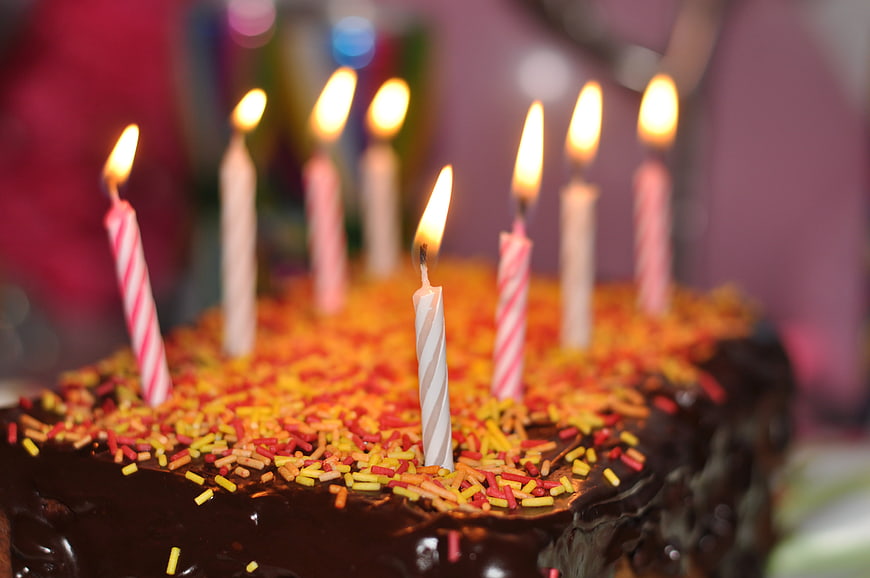 Chocolate birthday cake with colorful sprinkles and lit candles