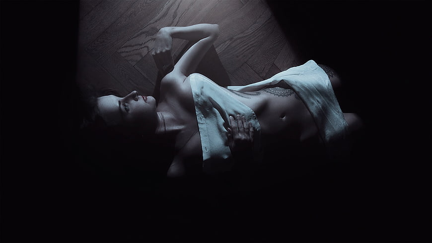 Dark moody portrait of a woman lying on a wooden floor