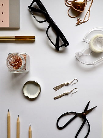 Flat lay of office supplies, jewelry, and stationery on white background