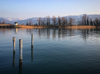Serene lake landscape with wooden posts and distant mountains