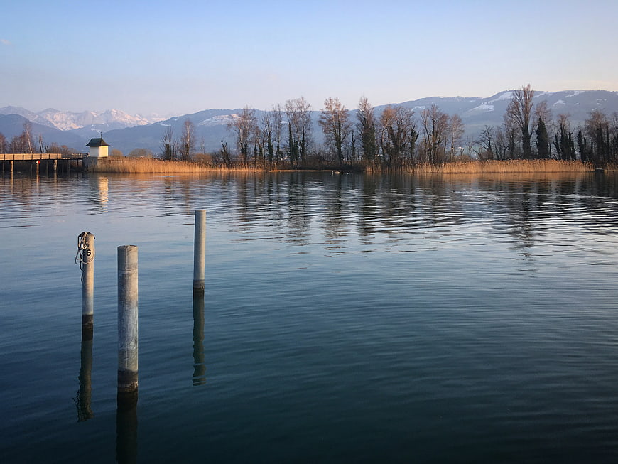 Serene lake landscape with wooden posts and distant mountains