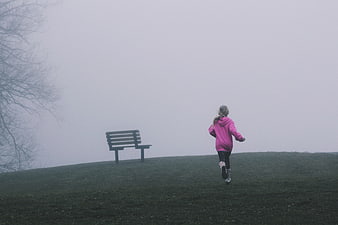 Child Running in Pink Hoodie on Foggy Park Hill