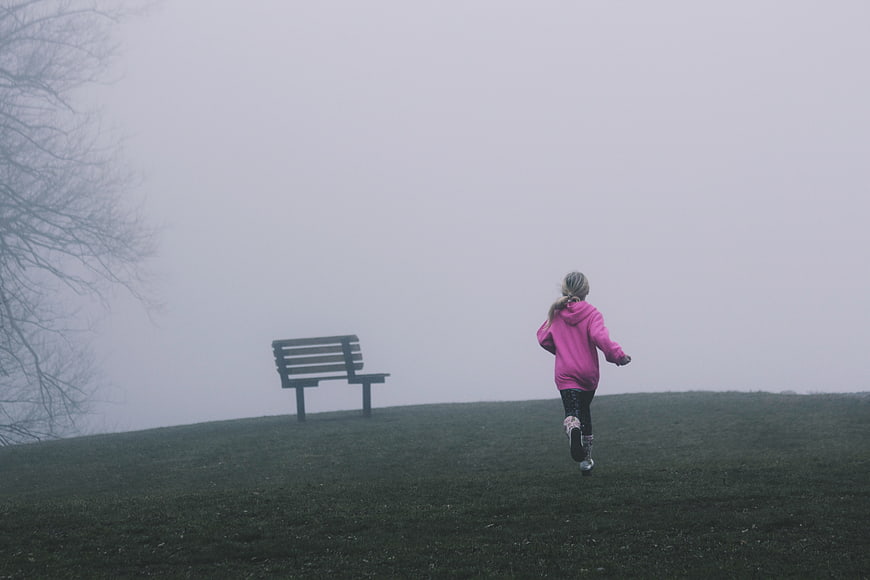 Child Running in Pink Hoodie on Foggy Park Hill
