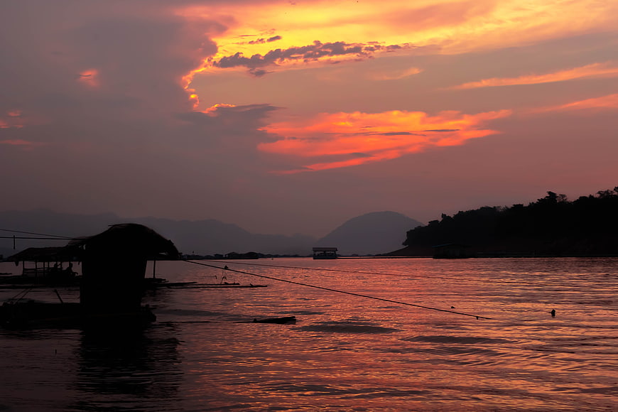 Silhouette of floating huts on lake at sunset