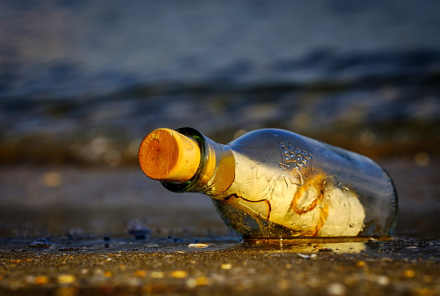 Message in a bottle on wet sand beach at sunset
