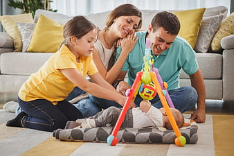Happy family playing with baby on living room floor