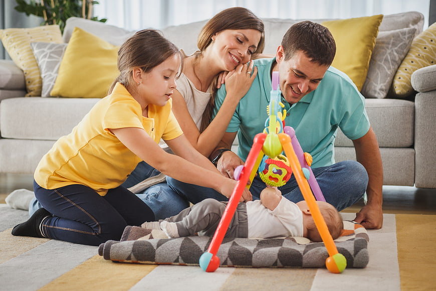 Happy family playing with baby on living room floor