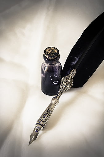 Vintage silver quill pen and ink bottle on white fabric