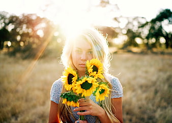 Blonde Woman Holding Sunflowers in Golden Hour Field
