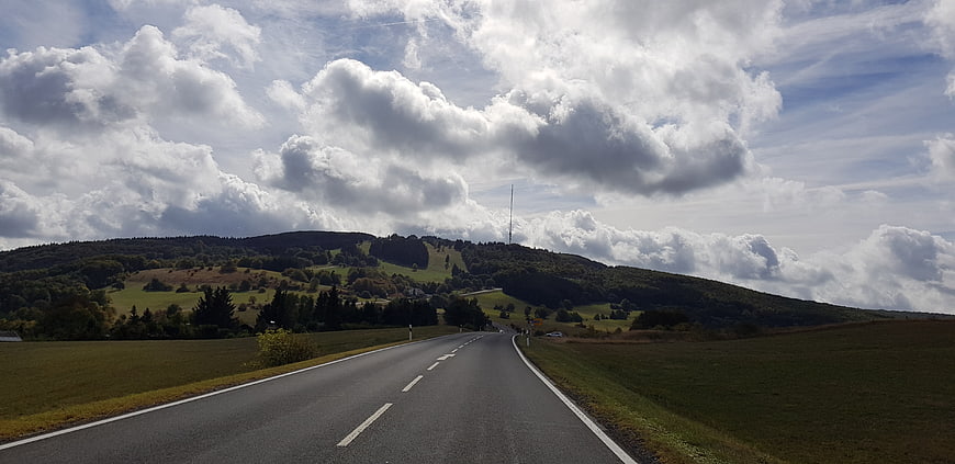 Winding country road through green hills under dramatic cloudy sky