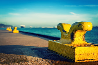 Yellow Harbor Bollard On Concrete Pier Near Sea