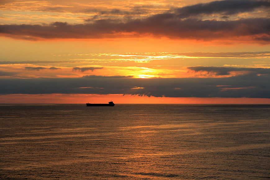 Silhouette of cargo ship on calm sea at sunset