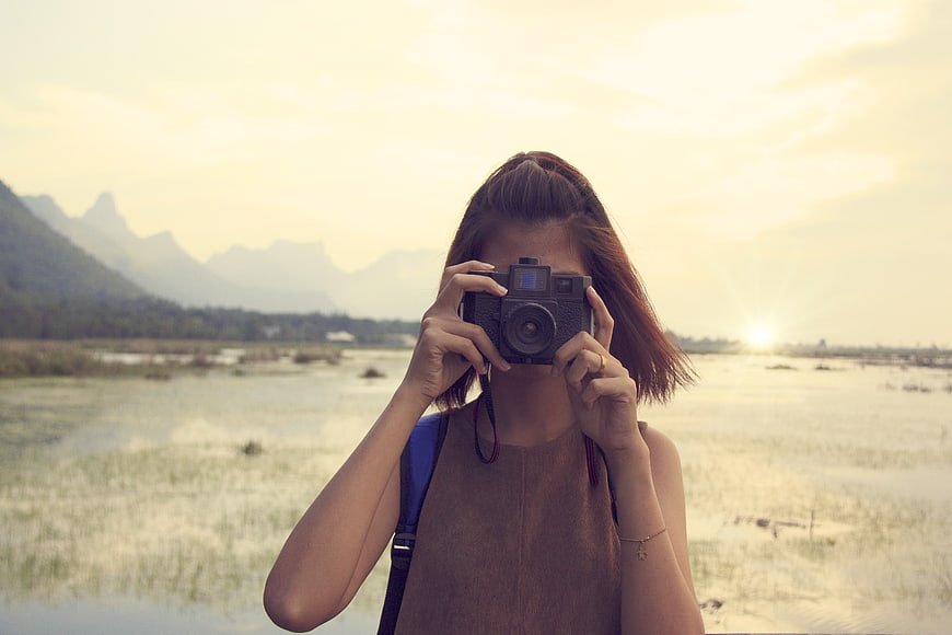 Woman photographer taking photo in rice field at sunrise