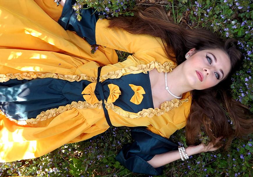 Woman in Yellow and Blue Dress Lying on a Grass Field