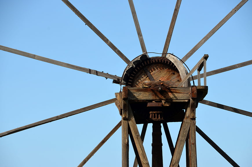 Close-up of vintage wooden windmill against blue sky