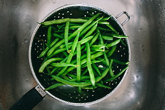 Fresh green beans in metal colander top view