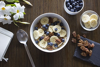 Overhead view of healthy oatmeal bowl with bananas, blueberries, and pecans