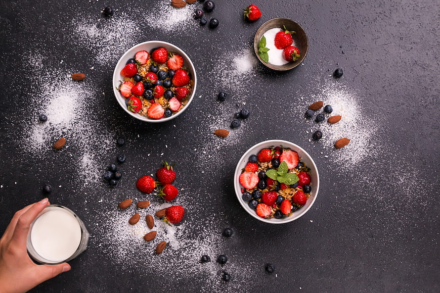 Overhead view of healthy breakfast bowls with berries and milk
