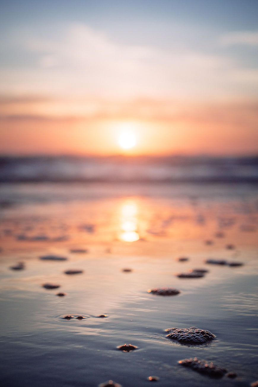 Serene Sunset Reflection on Wet Sandy Beach with Bubbles