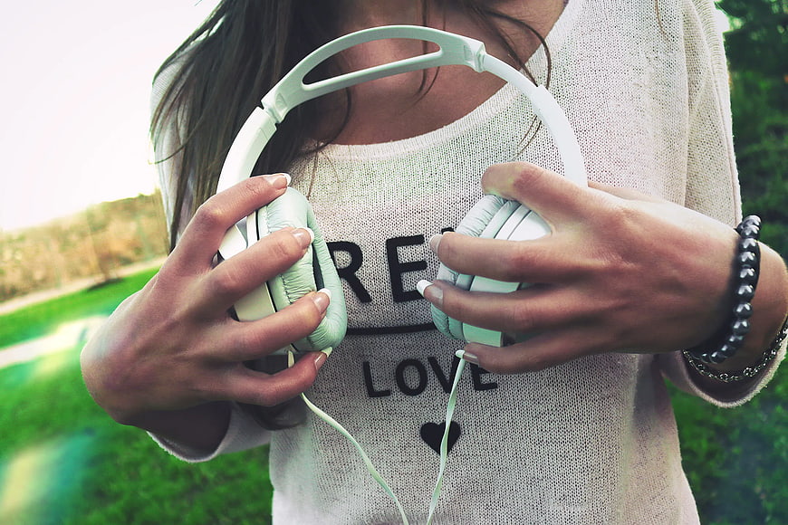 Woman Holding White Headphones in Park